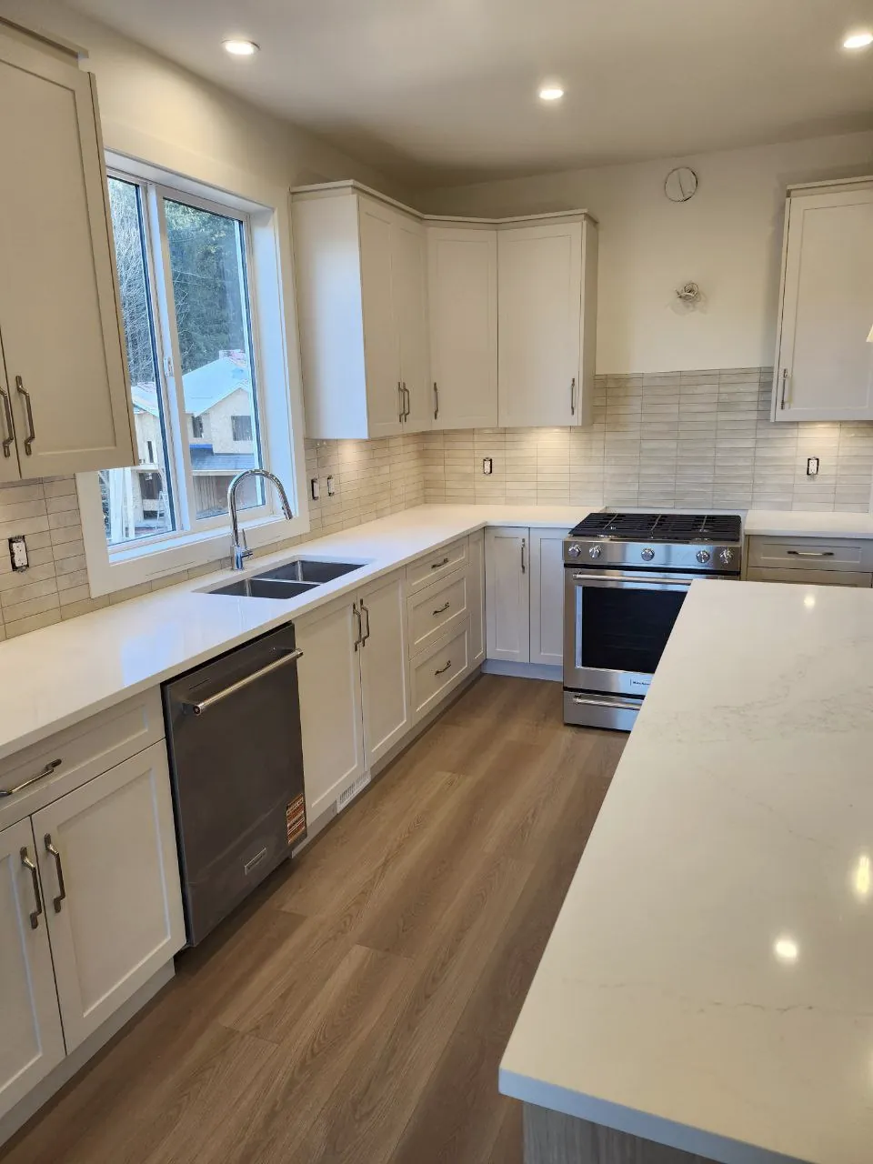 Bright open-plan kitchen with quartz waterfall island by NovoTile, Greater Victoria
