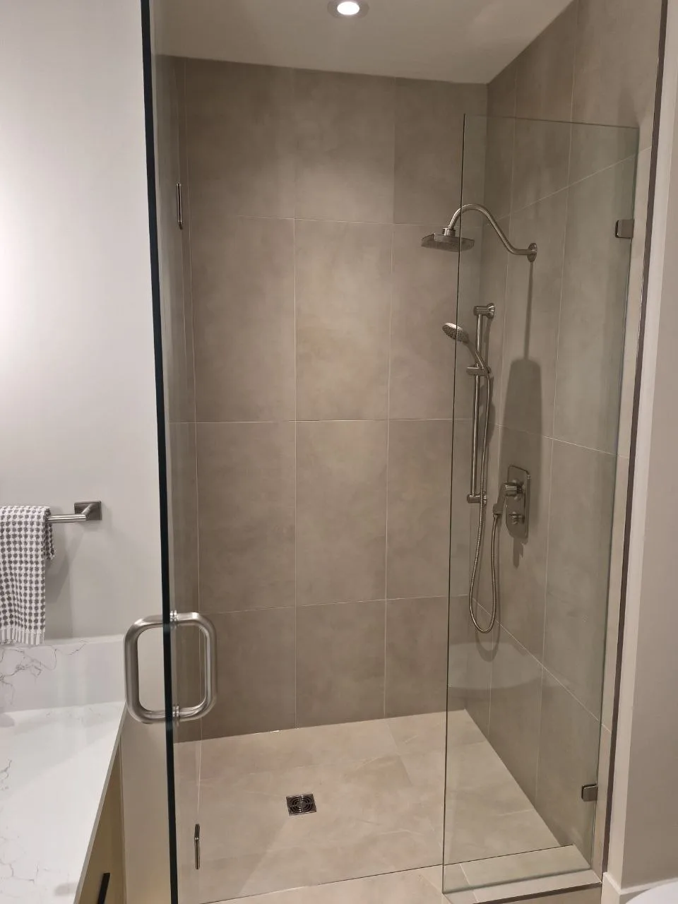 Large-format porcelain walk-in shower with frameless glass door and centre drain, Greater Victoria