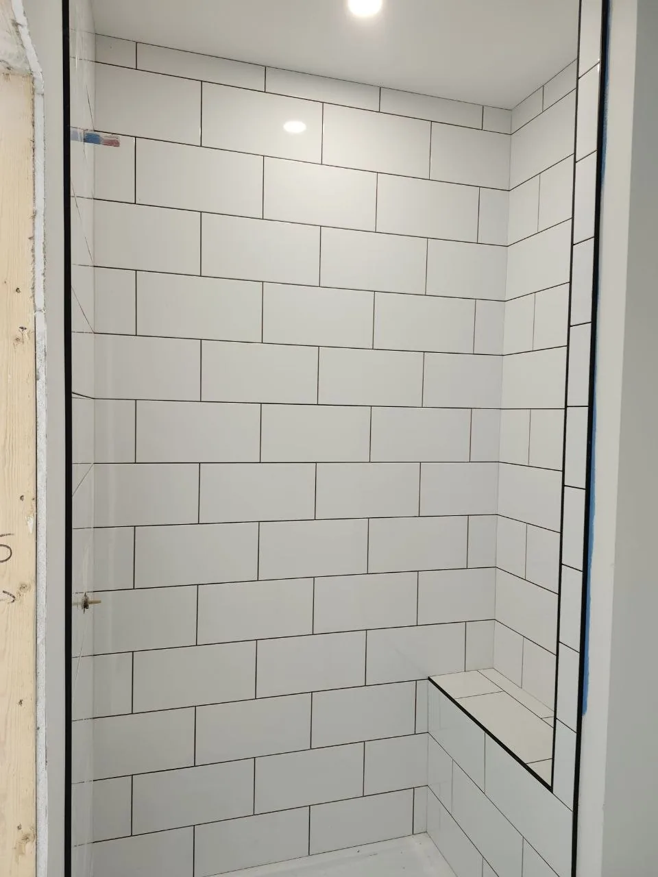 White subway-tile walk-in shower with black trim